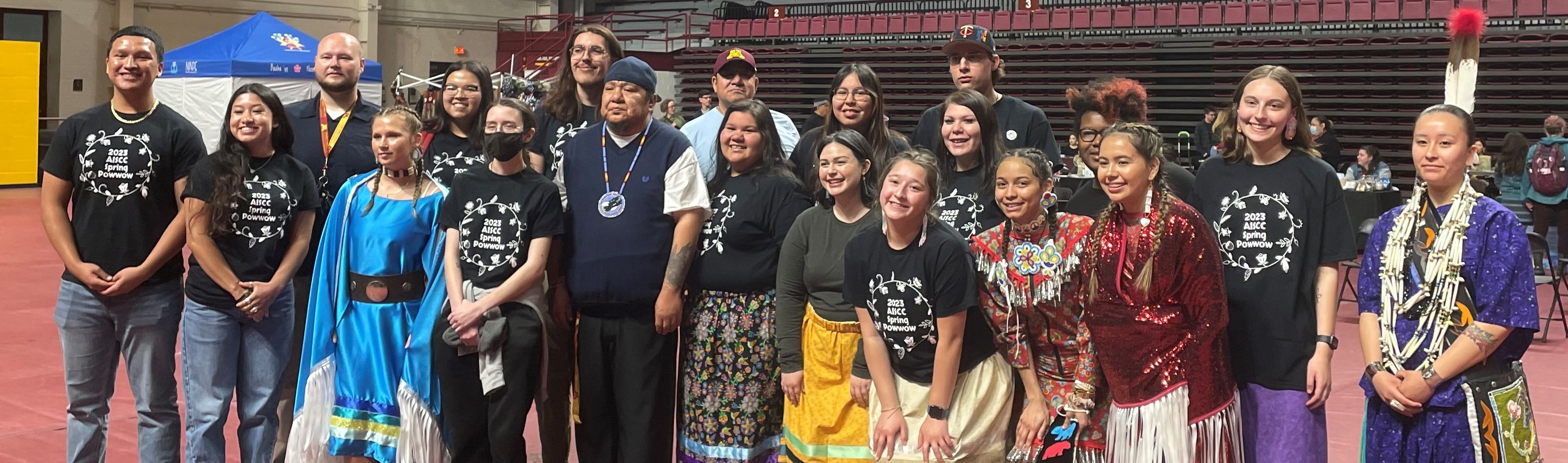 Members of the 2022-2023 AISCC Board stand alongside American Indian and Indigenous graduates during a University Graduates honor and recognition. Photographed at the UMNTC 2023 Spring Powwow